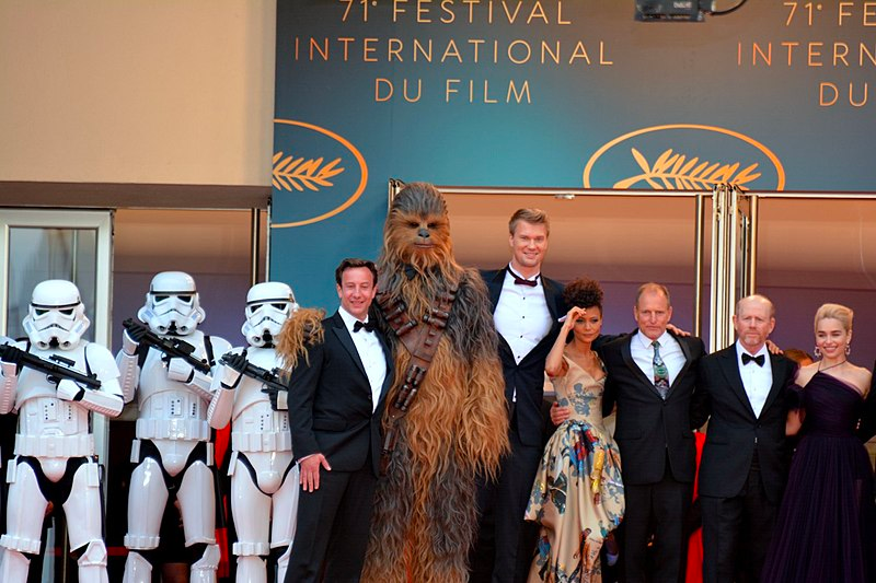 Producer Simon Emanuel; actors Joonas Suotamo, Thandie Newton, and Woody Harrelson; director Ron Howard; and actor Emilia Clarke at the Cannes film festival in 2018 for the promotion of Solo: A Star Wars Story. Photo by Georges Biard is licensed under CC BY-SA 4.0.